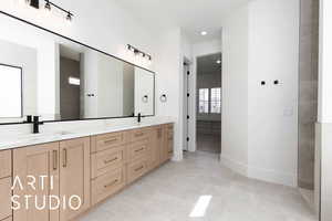 Bathroom featuring double vanity, baseboards, and recessed lighting