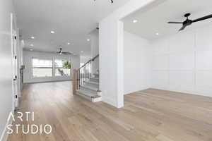 Staircase with ceiling fan, recessed lighting, wood finished floors, baseboards, and a decorative wall