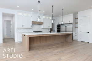 Kitchen featuring built in appliances, light countertops, white cabinetry, decorative backsplash, and recessed lighting