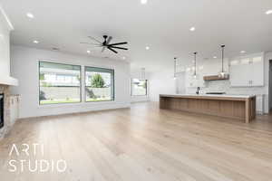 Unfurnished living room with a ceiling fan, a fireplace, light wood finished floors, recessed lighting, and baseboards