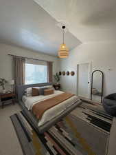 Carpeted bedroom with a textured ceiling and vaulted ceiling