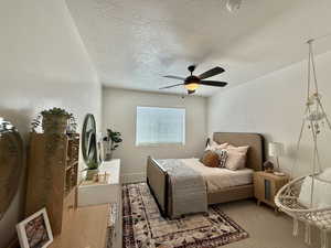 Bedroom featuring a textured ceiling, ceiling fan, and light colored carpet