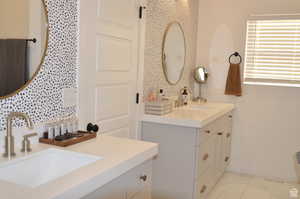 Bathroom featuring marble look tiles, vanity, and baseboards