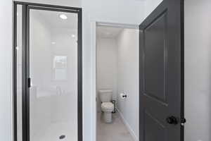 Full bath with baseboards, a stall shower, and toilet