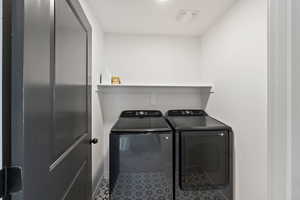 Clothes washing area featuring washer and clothes dryer, baseboards, and tile patterned floors