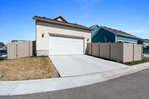 View of front of home featuring fence, driveway, stucco siding, and an attached garage