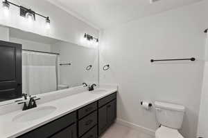 Bathroom with toilet, baseboards, double vanity, tile patterned floors, and a textured ceiling