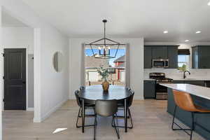 Dining area with a chandelier, light wood finished floors, baseboards, and recessed lighting