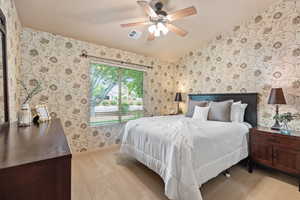 Bedroom with light colored carpet, wallpapered walls, a ceiling fan, and baseboards