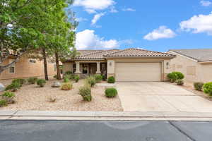 View of front facade with an attached garage, stucco siding, driveway, and a tiled roof