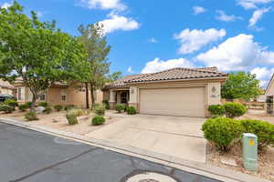Mediterranean / spanish home featuring a tile roof, driveway, a garage, stucco siding, and fence