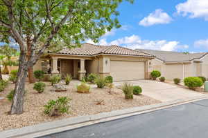 View of front of property featuring an attached garage, a tile roof, driveway, stucco siding, and covered porch