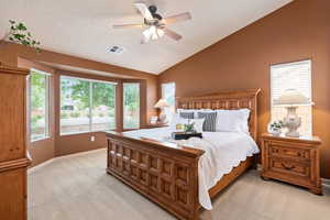 Bedroom with light carpet, vaulted ceiling, baseboards, and ceiling fan