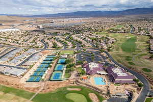 Aerial overview of property's location featuring a mountainous background, a golf course, and nearby suburban area