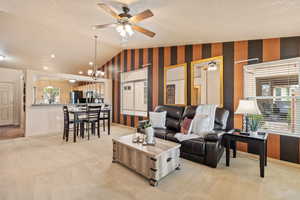 Living room with healthy amount of natural light, lofted ceiling, ceiling fan, light colored carpet, and a chandelier