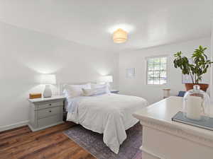 Bedroom featuring dark wood-style flooring and baseboards