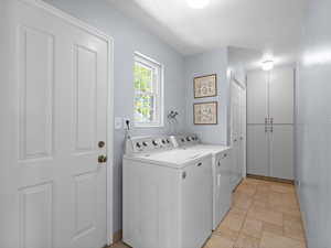 Washroom featuring separate washer and dryer and light stone finish floors