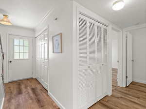 Hallway featuring wood finished floors, a textured ceiling, crown molding, and baseboards