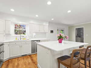 Kitchen with a sink, appliances with stainless steel finishes, a kitchen bar, ornamental molding, and a kitchen island