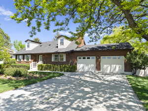 New england style home featuring concrete driveway, a garage, and brick siding