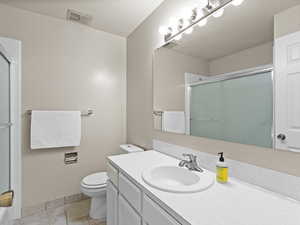 Full bath featuring a shower with door, toilet, baseboards, and vanity