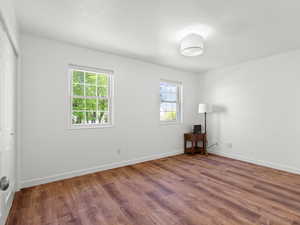 Unfurnished room with wood finished floors, healthy amount of natural light, and baseboards
