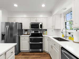 Kitchen featuring stainless steel appliances, a sink, tasteful backsplash, white cabinetry, and light countertops