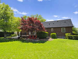Back of house with a yard, a deck, stairs, and roof with shingles