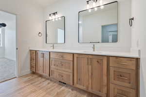 Full bath featuring wood finished floors, double vanity, and baseboards