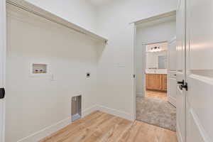 Washroom with washer hookup, light wood-style flooring, hookup for an electric dryer, and baseboards