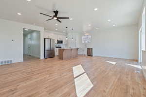 Kitchen with stainless steel appliances, open floor plan, a kitchen island, light countertops, and recessed lighting