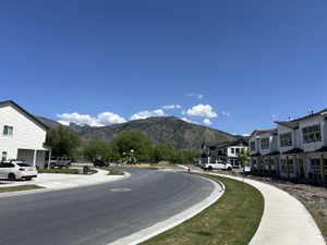 View of asphalt road featuring a mountain view, sidewalks, and a residential view