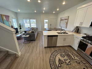 Kitchen with stainless steel appliances, a sink, wood finished floors, a peninsula, and open floor plan