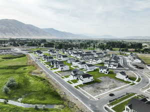 Aerial view of property and surrounding area featuring a mountainous background and nearby suburban area