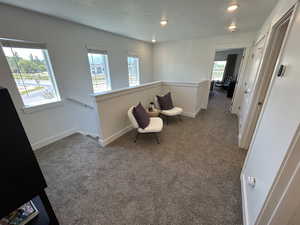 Sitting room featuring an upstairs landing, carpet floors, healthy amount of natural light, baseboards, and recessed lighting