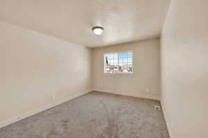 Unfurnished room with a textured ceiling, carpet, and baseboards