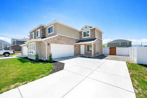 Traditional home featuring a garage, driveway, stucco siding, brick siding, and stone siding