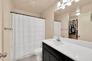 Full bath with tile patterned floors, vanity, toilet, a spacious closet, and a shower with shower curtain