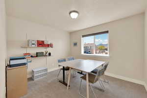 Dining area featuring carpet flooring, baseboards, and a textured ceiling
