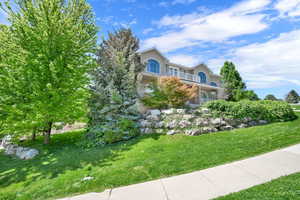 View of front of house with a front yard and a balcony