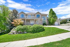 View of front of home featuring french doors, concrete driveway, stucco siding, a front yard, and a balcony