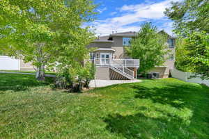 Back of property with stucco siding, stairs, cooling unit, a wooden deck, and a patio area