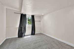 Carpeted spare room featuring baseboards and a textured ceiling