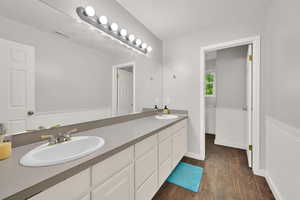 Bathroom with wood finished floors, double vanity, and a wainscoted wall