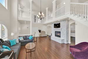 Living room featuring a towering ceiling, dark wood-type flooring, a fireplace, arched walkways, and a chandelier
