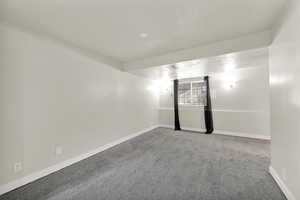 Carpeted spare room featuring baseboards