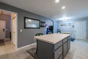 Kitchen with a center island, light countertops, arched walkways, light tile patterned floors, and recessed lighting