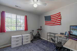 Carpeted office space with ceiling fan and baseboards