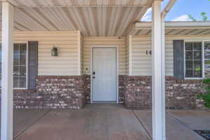 Entrance to property featuring brick siding and covered porch
