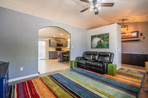 Living area with arched walkways, ceiling fan, lofted ceiling, and baseboards